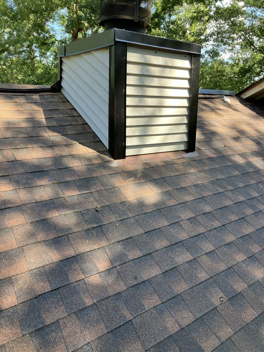 Chimney cricket and step flashing on a finished architectural shingle roof